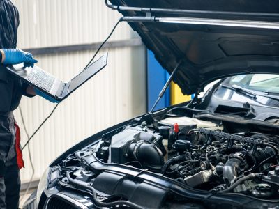Serviceman with laptop checks car software in car service.